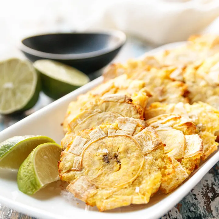 plated air fryer tostones on a rectangular white plate with lime wedges ready to enjoy