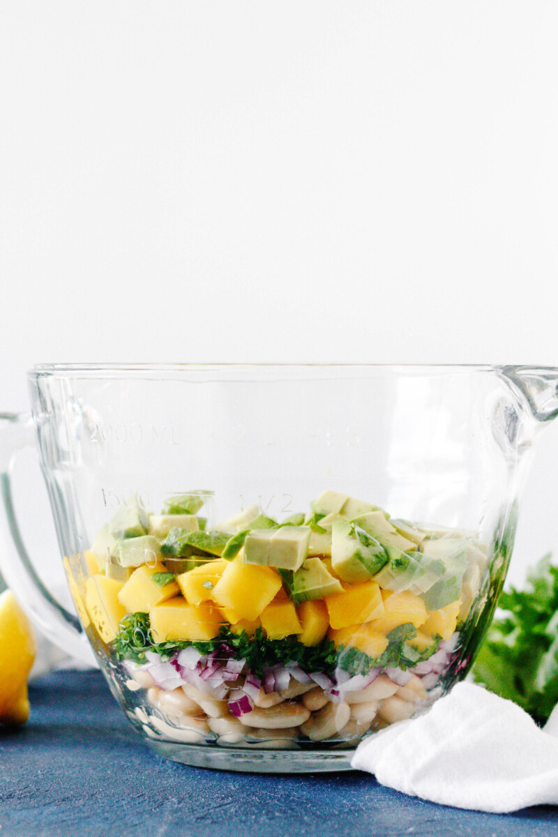 salad ingredients layered in a glass mixing bowl during preparation