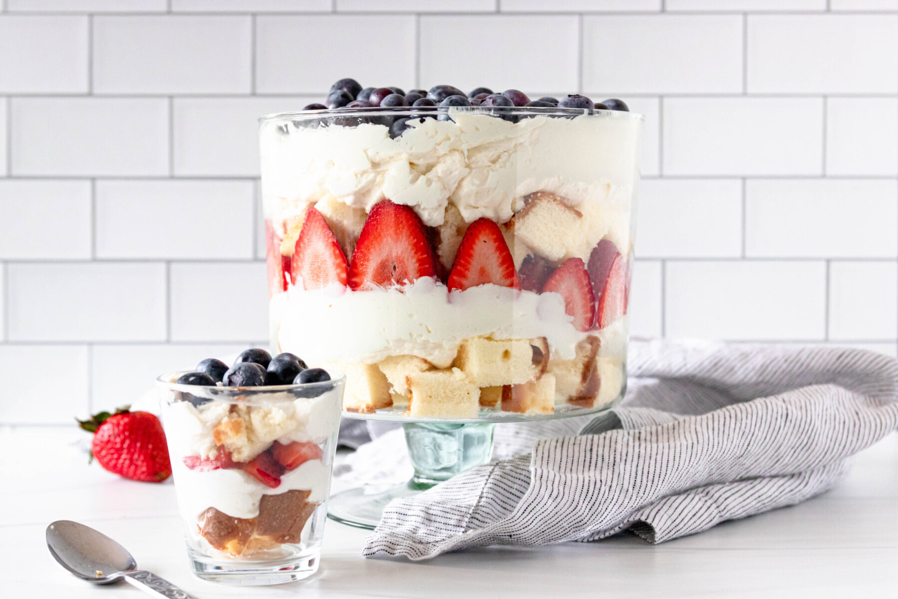 horizontal image of a large red white and blue cheesecake trifle next to a smaller individual trifle to show serving options