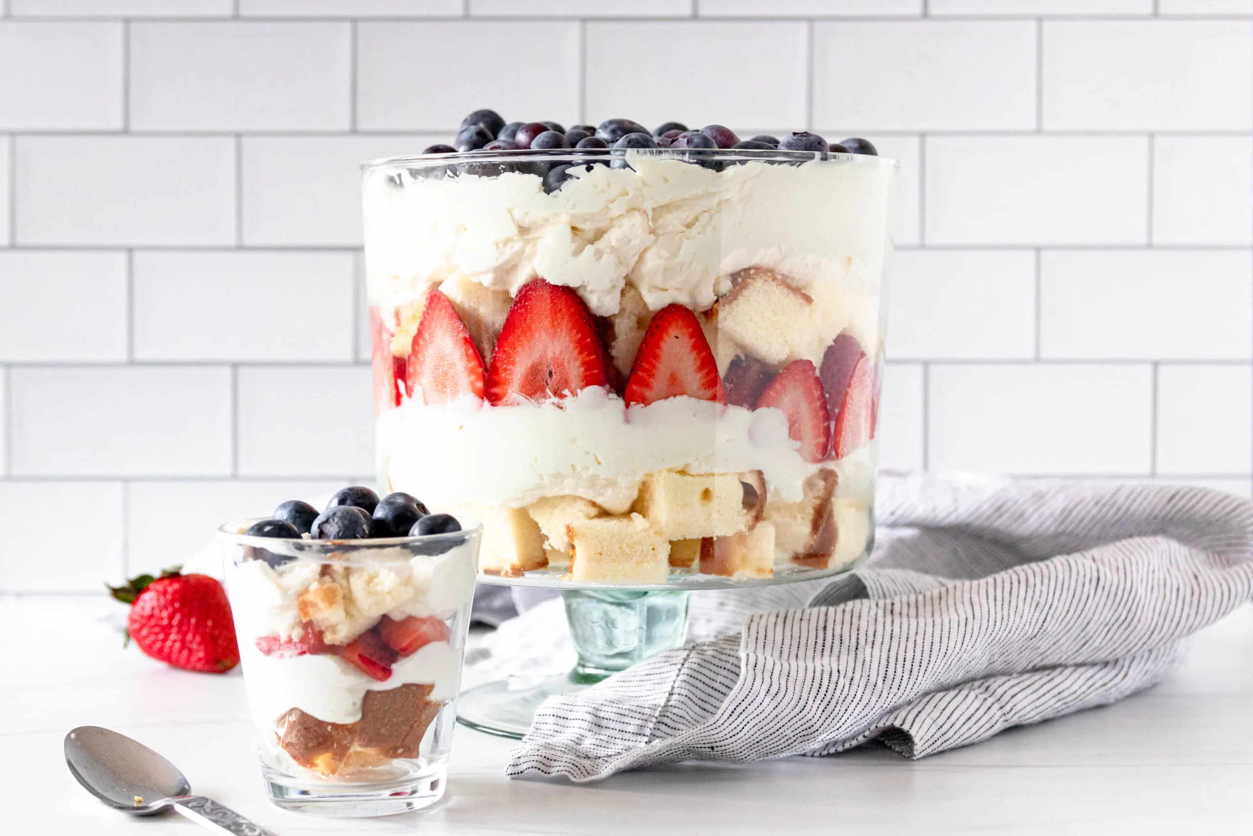 horizontal image of a large red white and blue cheesecake trifle next to a smaller individual trifle to show serving options