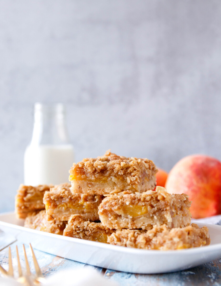 vertical image of 7 peach crumb squares on a serving plate