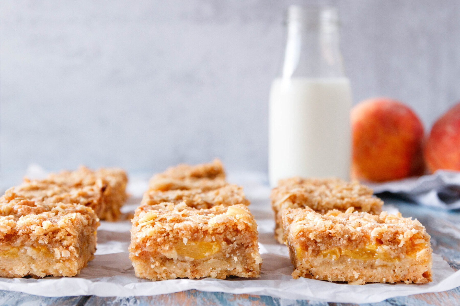 close up of the bars arranged in a single layer and sliced so you can see the base, peach, and crumb layers