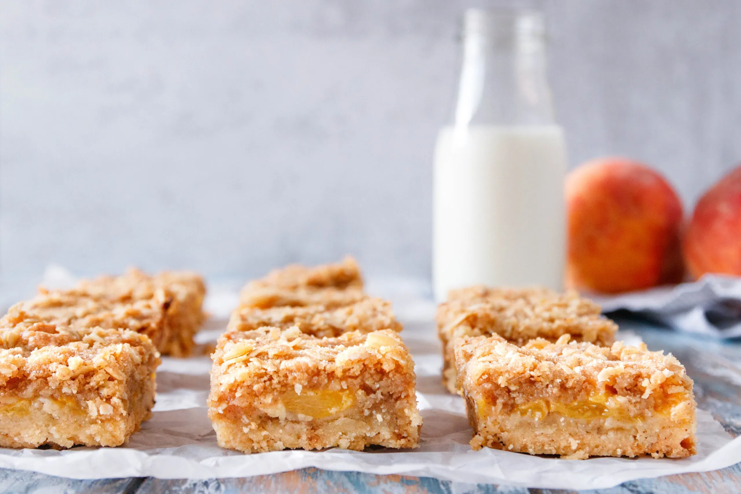 close up of the bars arranged in a single layer and sliced so you can see the base, peach, and crumb layers