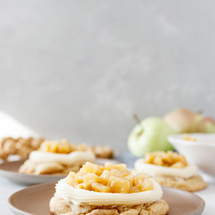 iced apple cookies, fully frosted and topped on individual dessert plants for serving. Grey background