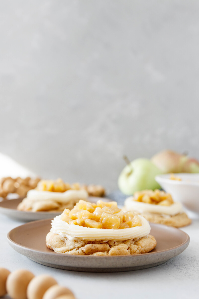 iced apple cookies, fully frosted and topped on individual dessert plants for serving. Grey background