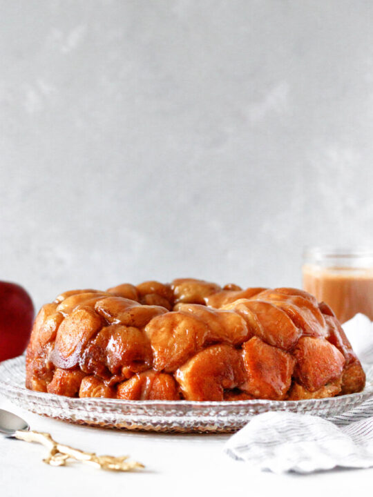 baked caramel apple monkey bread on a cut glass plate with a grey background