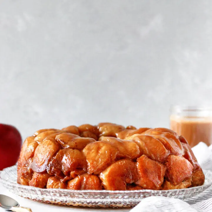baked caramel apple monkey bread on a cut glass plate with a grey background