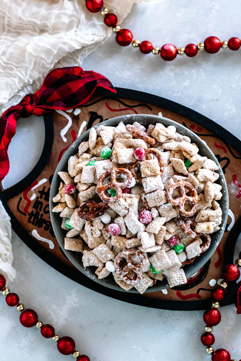 Overhead view of the Christmas Muddy Buddy Mix in a grey bowl on a "Cookies for Santa" tray. This is one serving suggestion