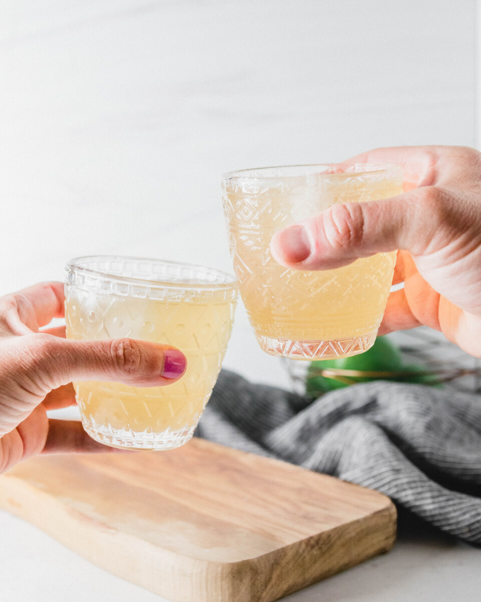 Picture of two hands holding the margarita glasses in a toasting gesture. 