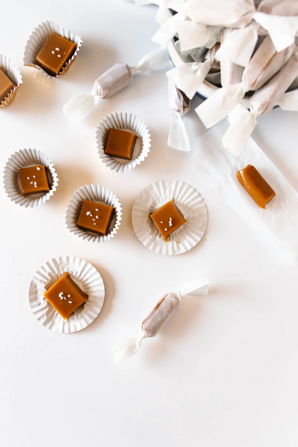 overhead view of the caramels - some wrapped in wax paper and some sitting in cupcake liners - scattered over a white surface