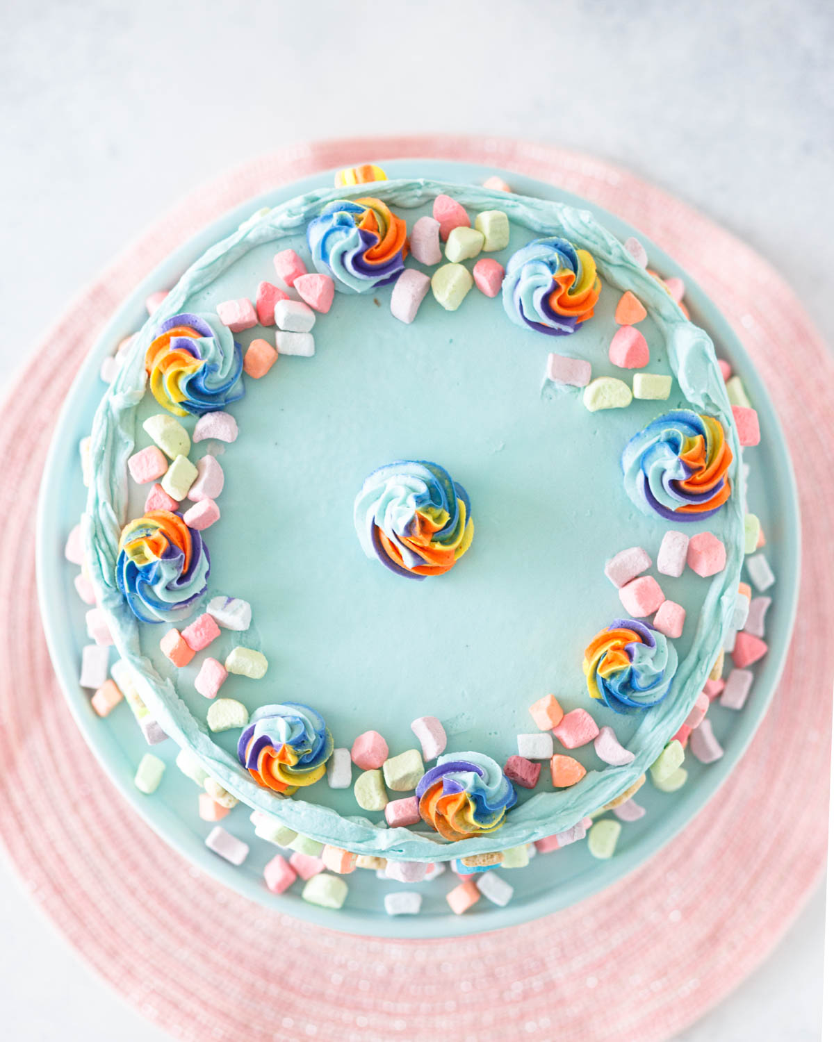 cake top view. The top of the cake is decorated with multicolored swirls and a ring of dehydrated marshmallows.