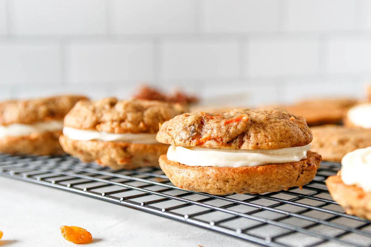 horizontal image of filled carrot cake cookies on a wire cooling rack