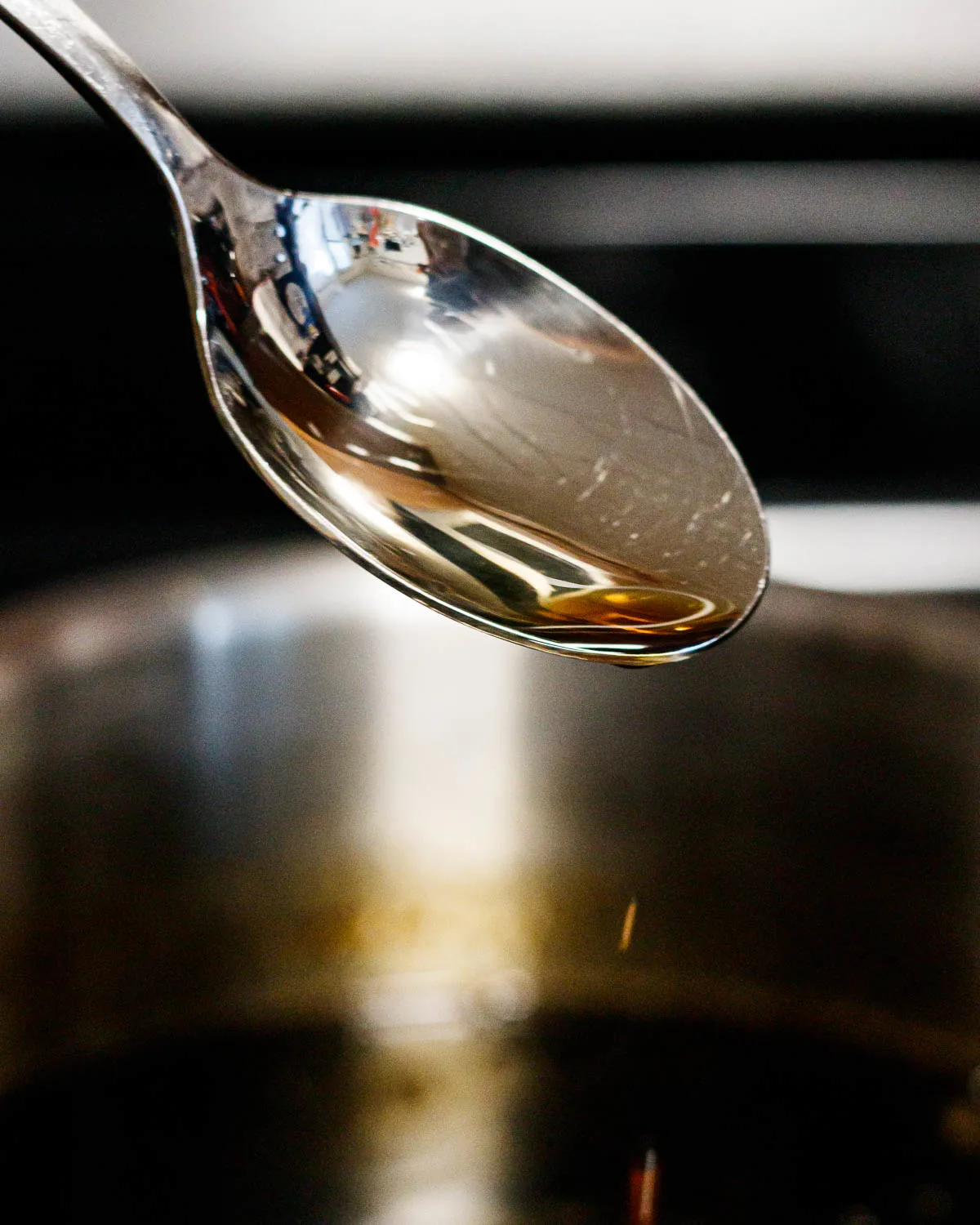 spoon lifting out of the sugar syrup to show the desired viscosity