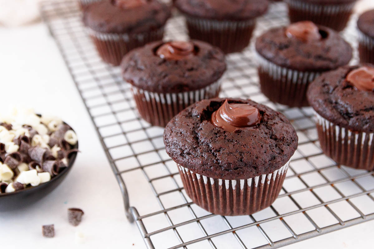 close up of triple chocolate cupcakes with the center cored and filled with chocolate ganache